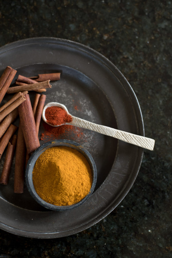 Spices in boel with spoon on black plate 