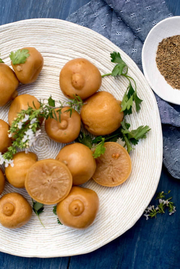 Perserved lemons on white plate with herbs